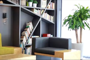 A modern living room with a dark grey sofa, a wooden coffee table, and a bookshelf filled with books.