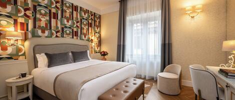 A modern hotel room with a large bed, a desk, a chair, and a decorative wall.