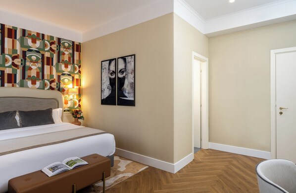 A hotel room with a large bed, a bedside table with a lamp, a chair, and artwork on the wall. - Leonardo Boutique Hotel Rome Monti (Rome)