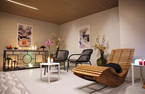 A modern lounge area with a wooden bench, two black chairs, a white table, and a console table with decorative items and candles. - Leonardo Boutique Hotel Rome Monti (Rome)