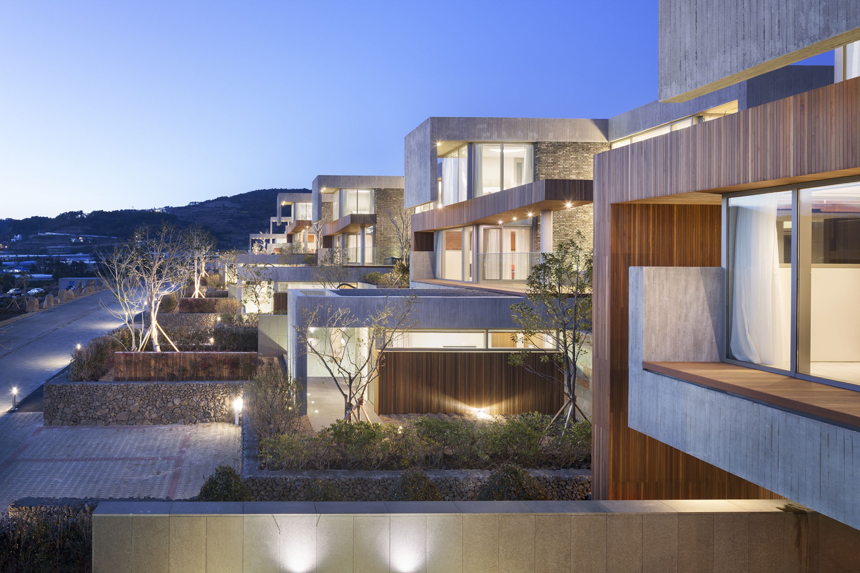 Um edifício residencial moderno com várias varandas, grandes janelas e uma área de entrada bem iluminada.