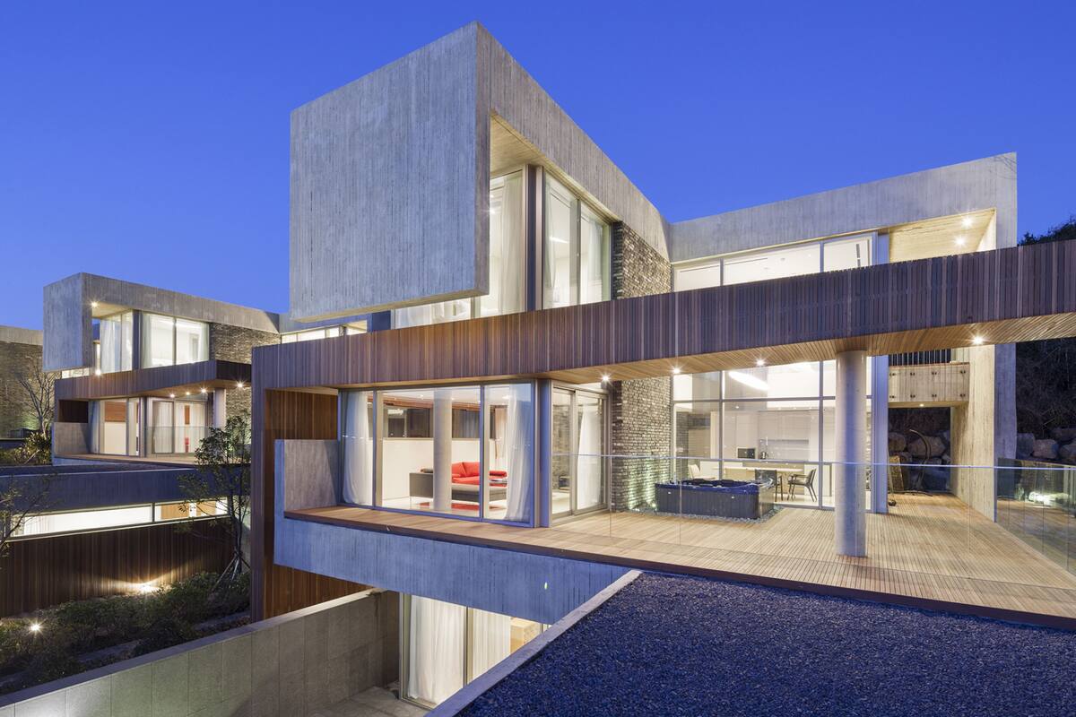 A modern multi-story house with large windows, a balcony, and a pool.