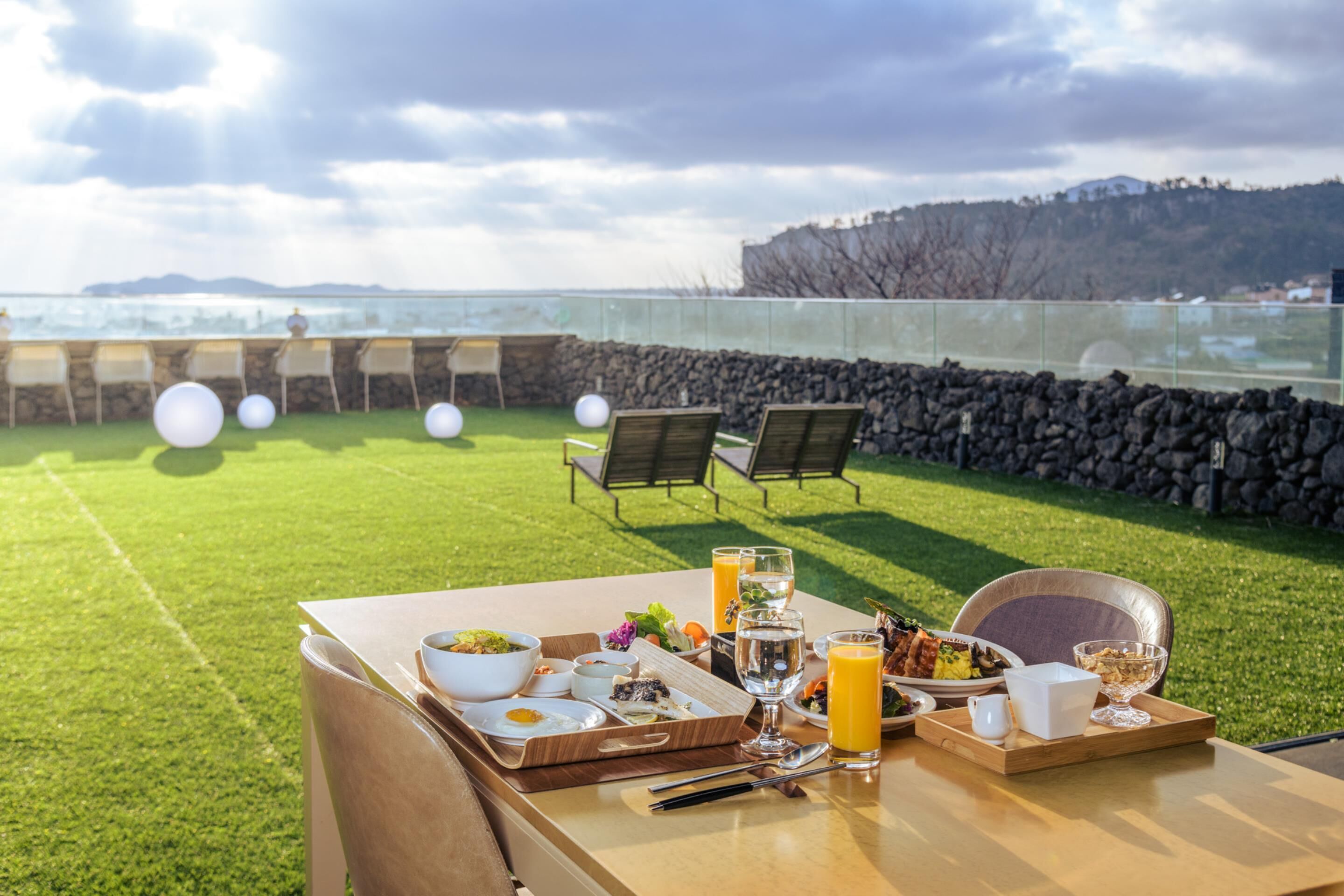 A dining table set with breakfast items and a scenic view of the sea.