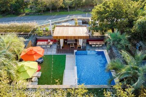 A rooftop pool area with a wooden deck, a small pool, and outdoor seating.