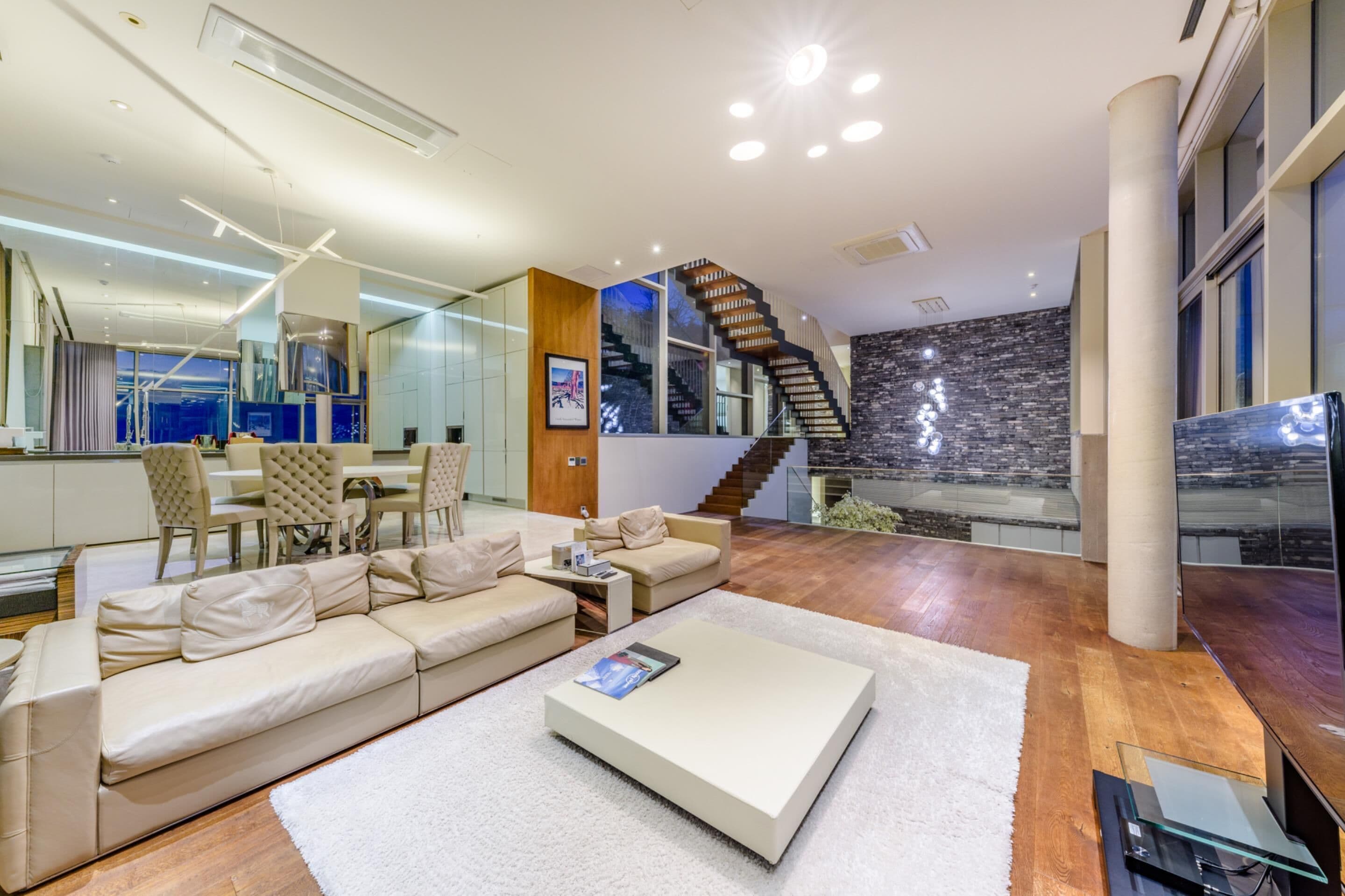A modern living room with a sofa, coffee table, and a staircase leading to an upper floor.
