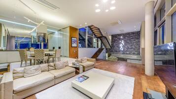 A modern living room with a sofa, coffee table, and a staircase leading to an upper floor.