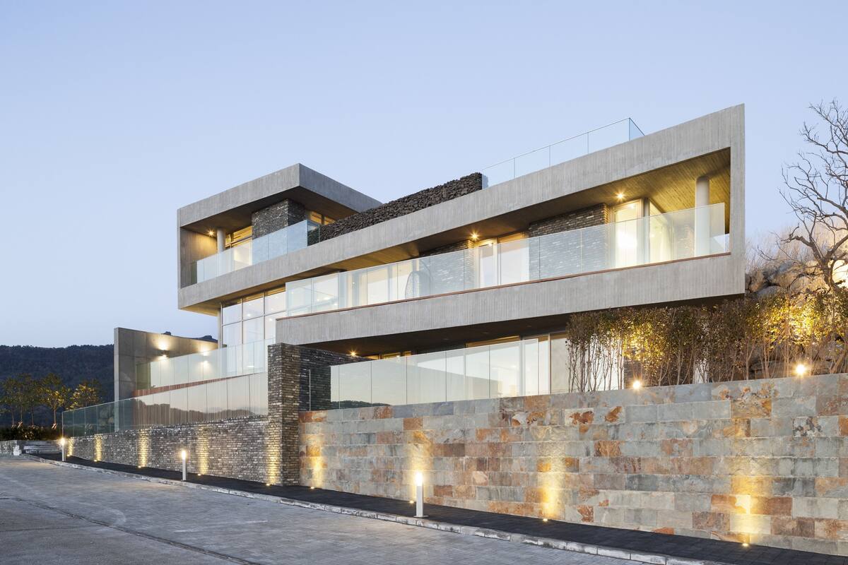 A modern multi-story building with a flat roof, large windows, and a stone facade.