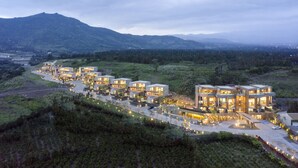 A modern hotel with multiple connected buildings, a landscaped courtyard, and a mountainous backdrop. - Bayhill Pool & Villa (Seogwipo)
