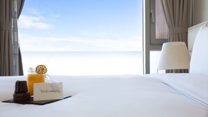 A hotel room with a bed, a welcome sign, a glass of orange juice, and a chocolate dessert. - Bayhill Pool & Villa (Seogwipo)