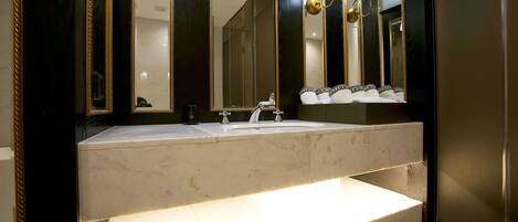 Un baño con un espejo grande, un lavamanos y un mueble de tocador.