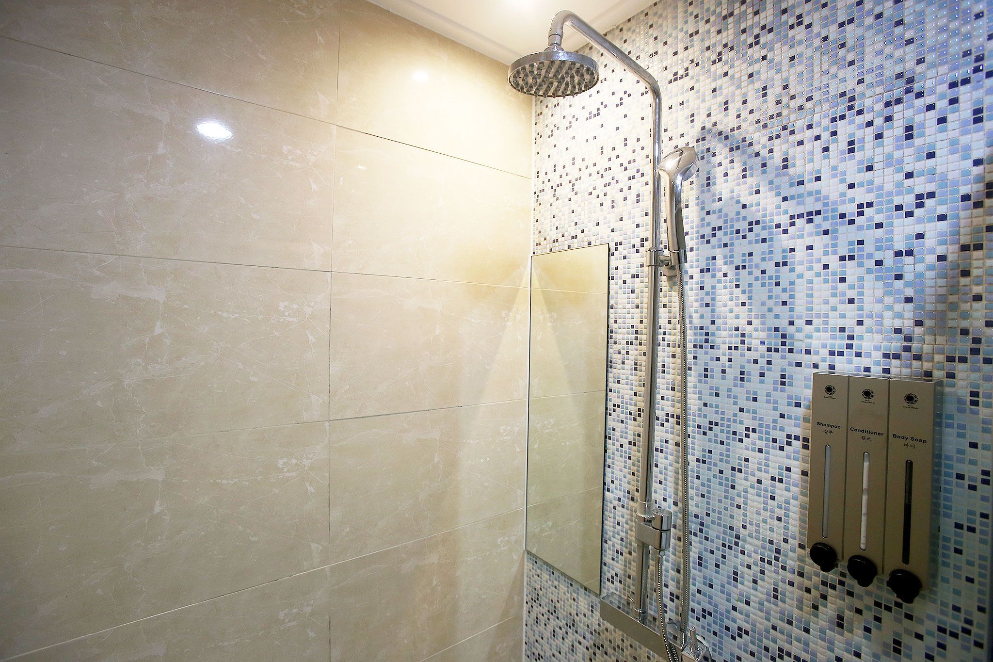 A modern bathroom with a shower, tiled walls, and a control panel for water temperature and flow.