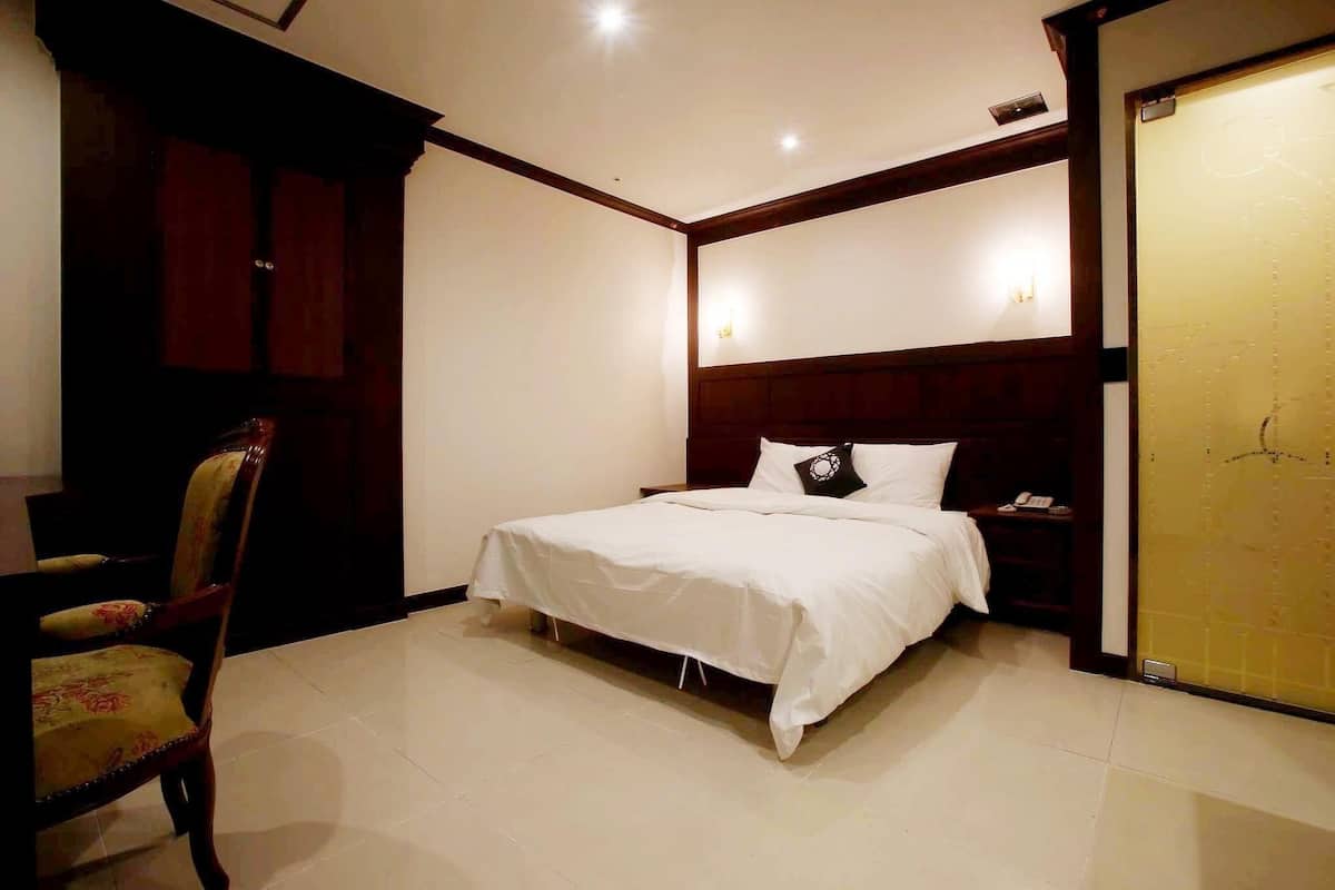 Une chambre à coucher comprenant un lit, une chaise, une table de chevet et une armoire.