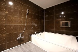 Un baño moderno con una bañera grande, un cabezal de ducha de mano y un panel de control en la pared.