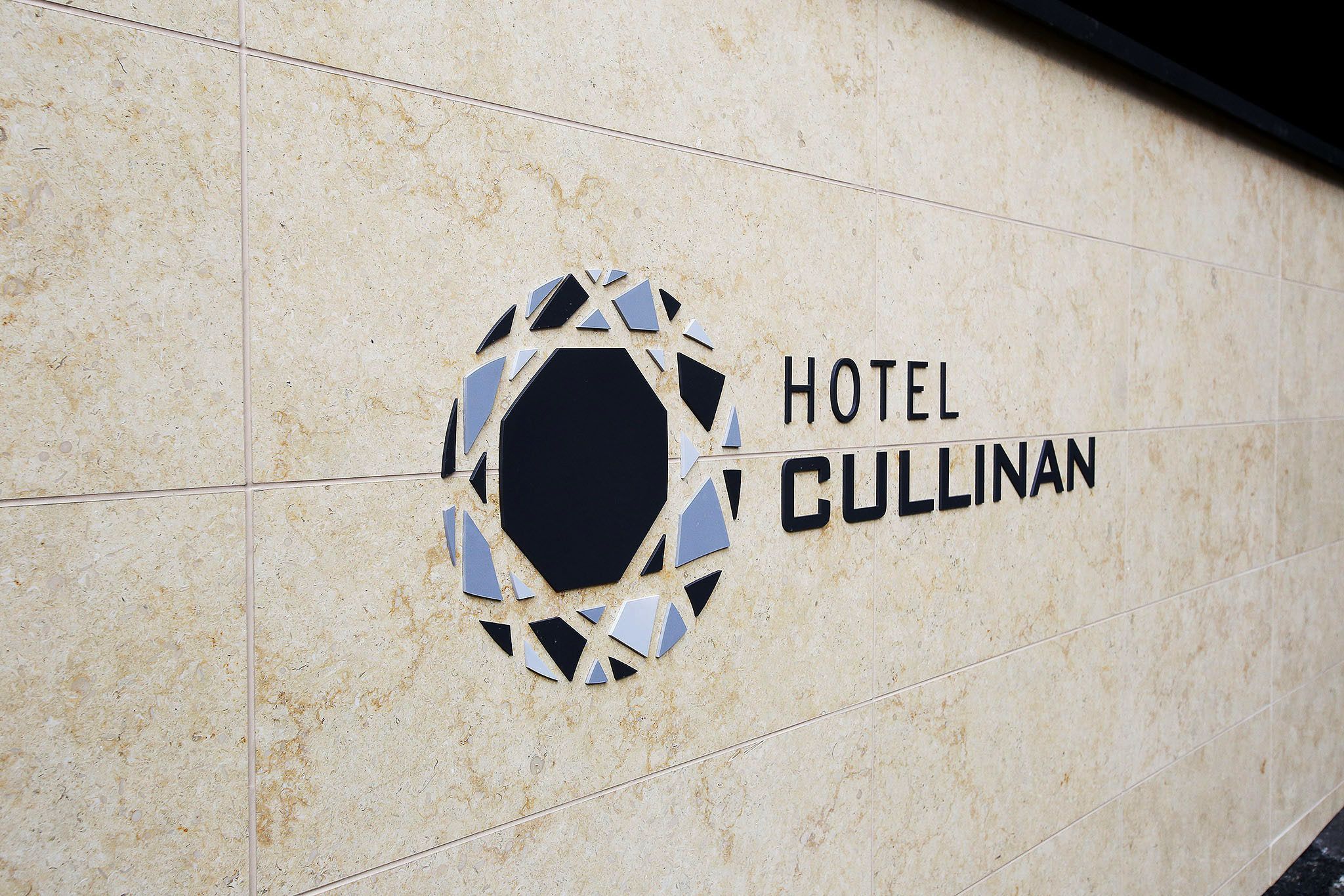 A hotel sign with a geometric logo and the name "HOTEL CULLINAN" on a tiled wall.