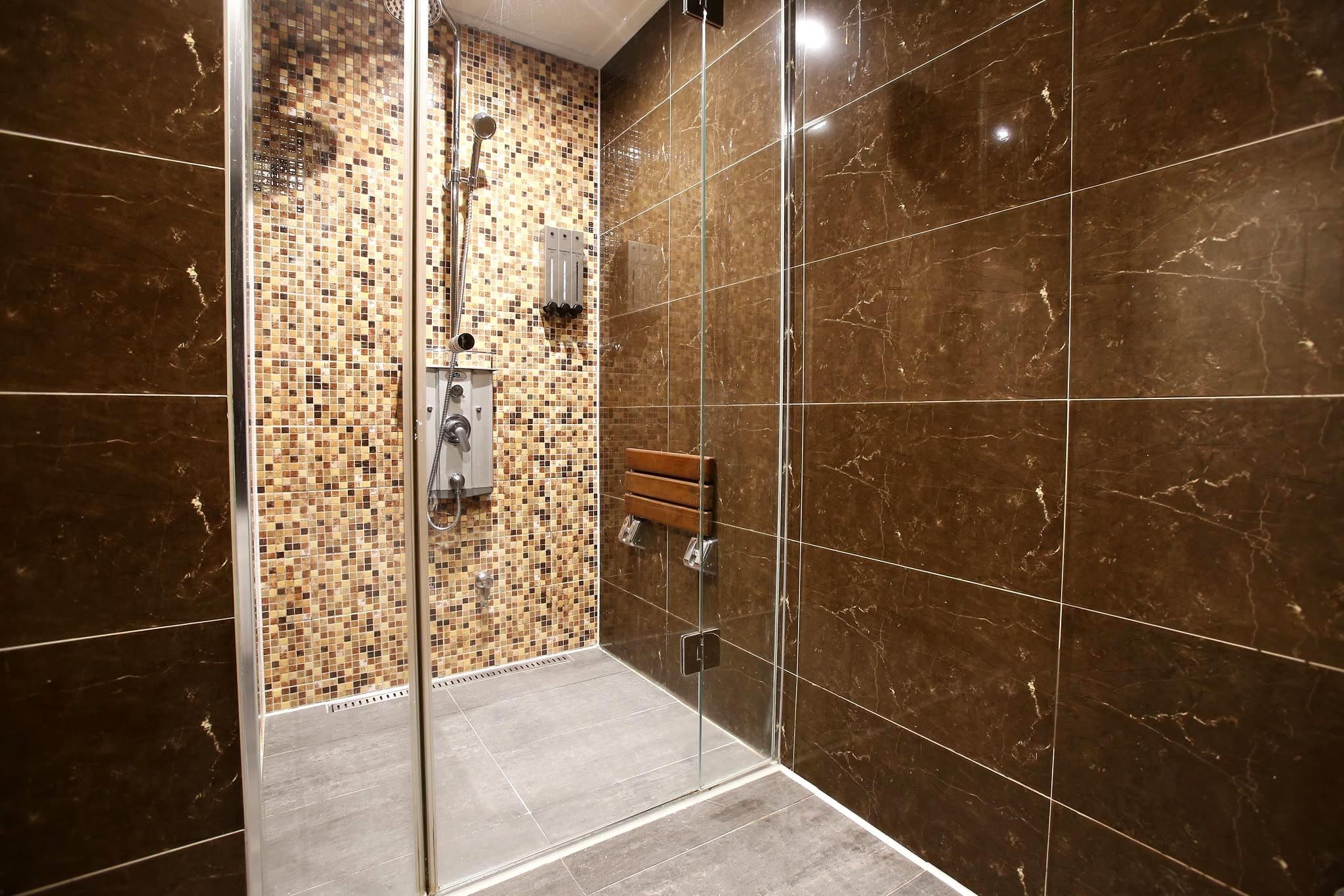 Un baño moderno con cabina de ducha de vidrio, pared de mosaicos y suelo de mármol.
