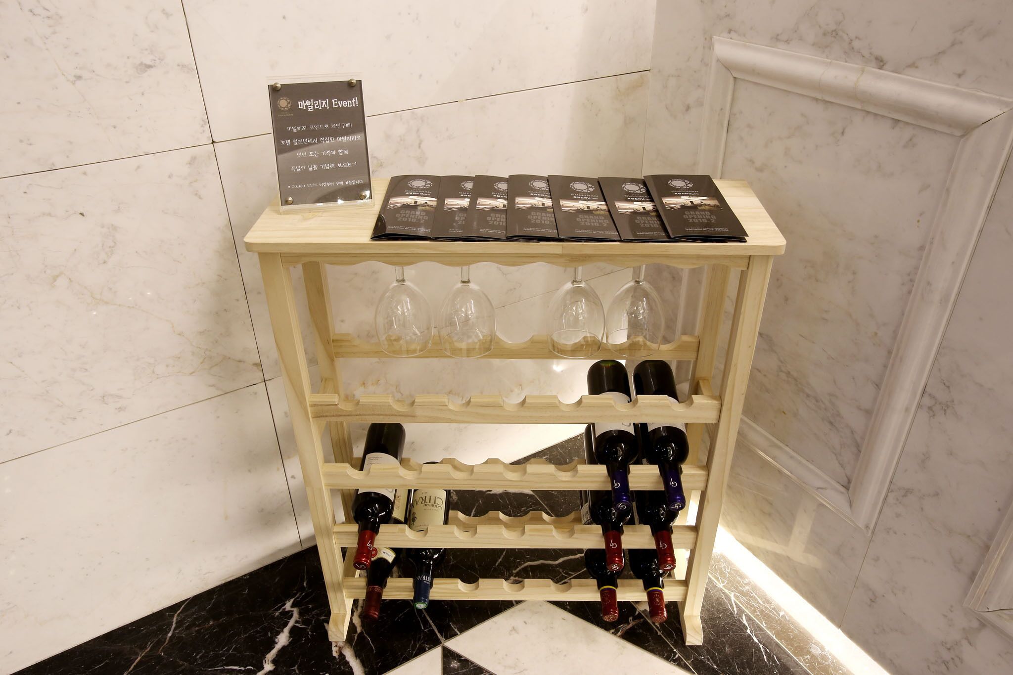 A wine display with multiple bottles and glasses on a wooden stand.