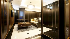 A luxurious room with dark wood paneling, a chandelier, a sofa with cushions, a coffee table, and a mirror. - Hotel Cullinan Yongin (Yongin)