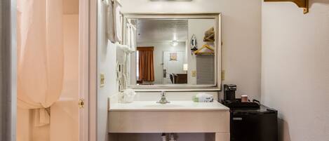 A bathroom with a sink, mirror, and shower curtain.