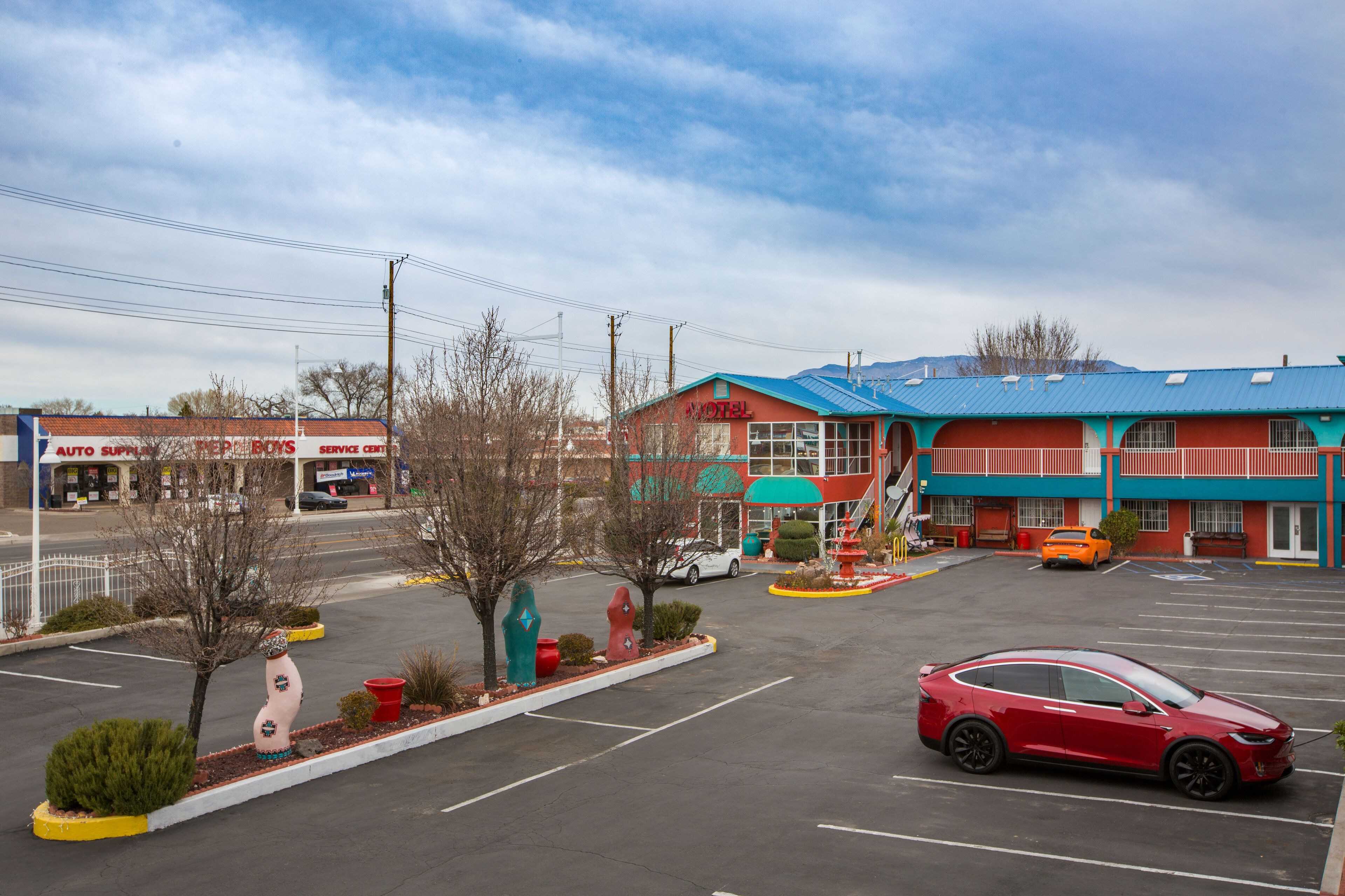 A motel with a blue roof and a service center across the street.