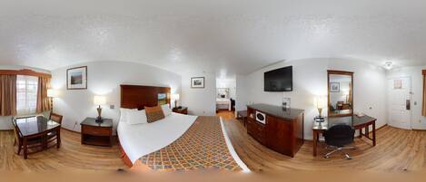 A hotel room with a bed, a desk, a dresser, a TV, and a bathroom.