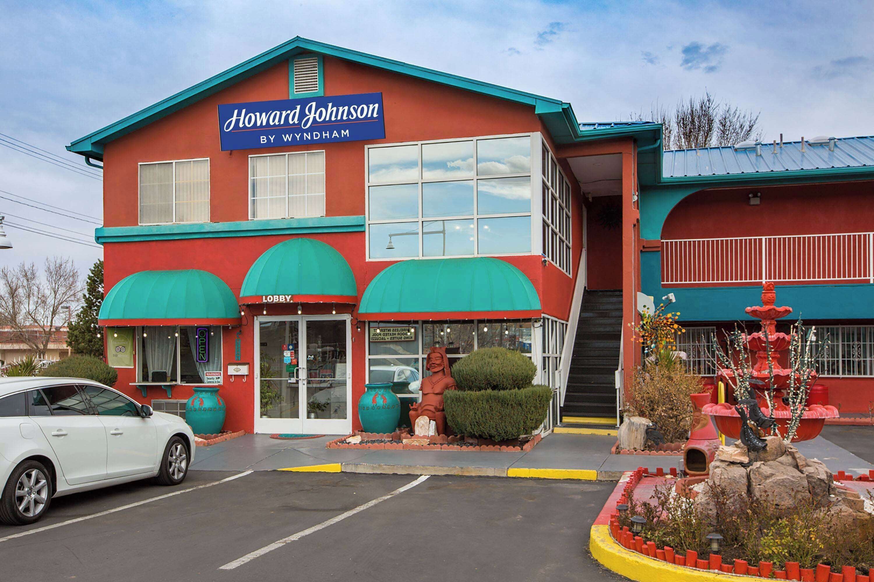 Un edificio de dos plantas con fachada roja y toldos verdes, identificado como "Howard Johnson By Wyndham".