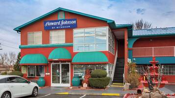 Un edificio de dos plantas con fachada roja y toldos verdes, identificado como "Howard Johnson By Wyndham".