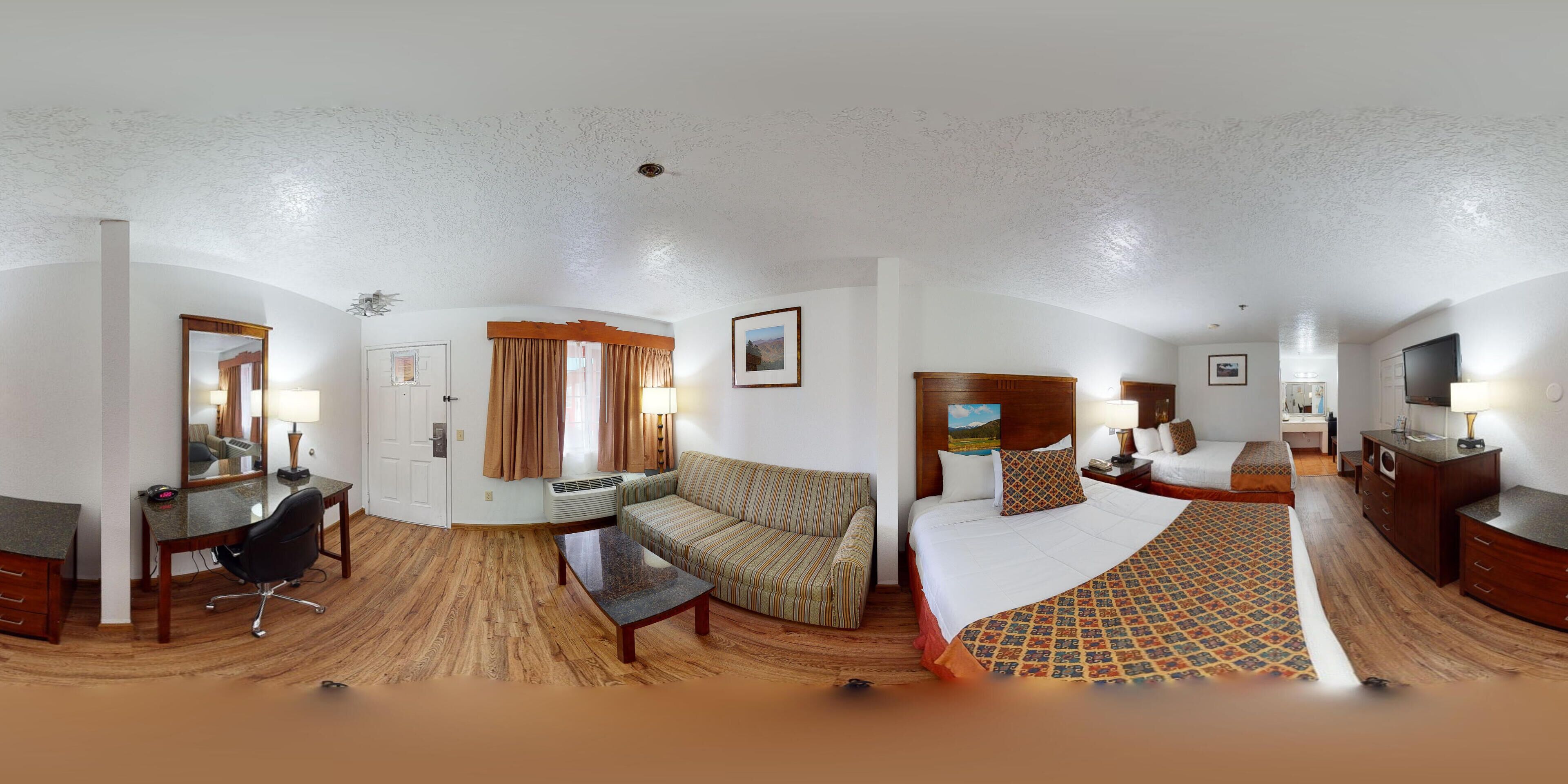 A hotel room with a bed, a sofa, a desk, and a chair.