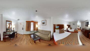 A hotel room with a bed, a sofa, a desk, and a chair.