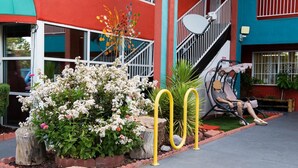 A building with a red facade, a staircase, and a seating area with a person. - Sandia Peak Inn Old Town ABQ, a Howard Johnson by Wyndham (Albuquerque)