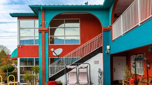A two-story building with a red and blue exterior, a staircase, and a satellite dish. - Sandia Peak Inn Old Town ABQ, a Howard Johnson by Wyndham (Albuquerque)