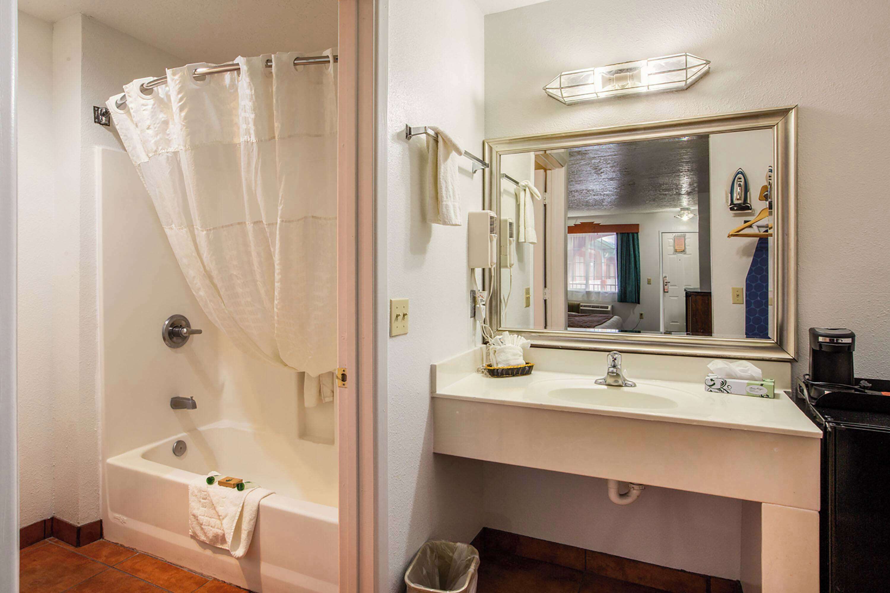 A bathroom with a bathtub, a sink, a mirror, and a towel rack.