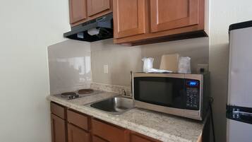 A compact kitchen with a stainless steel microwave, a built-in oven, and a refrigerator.