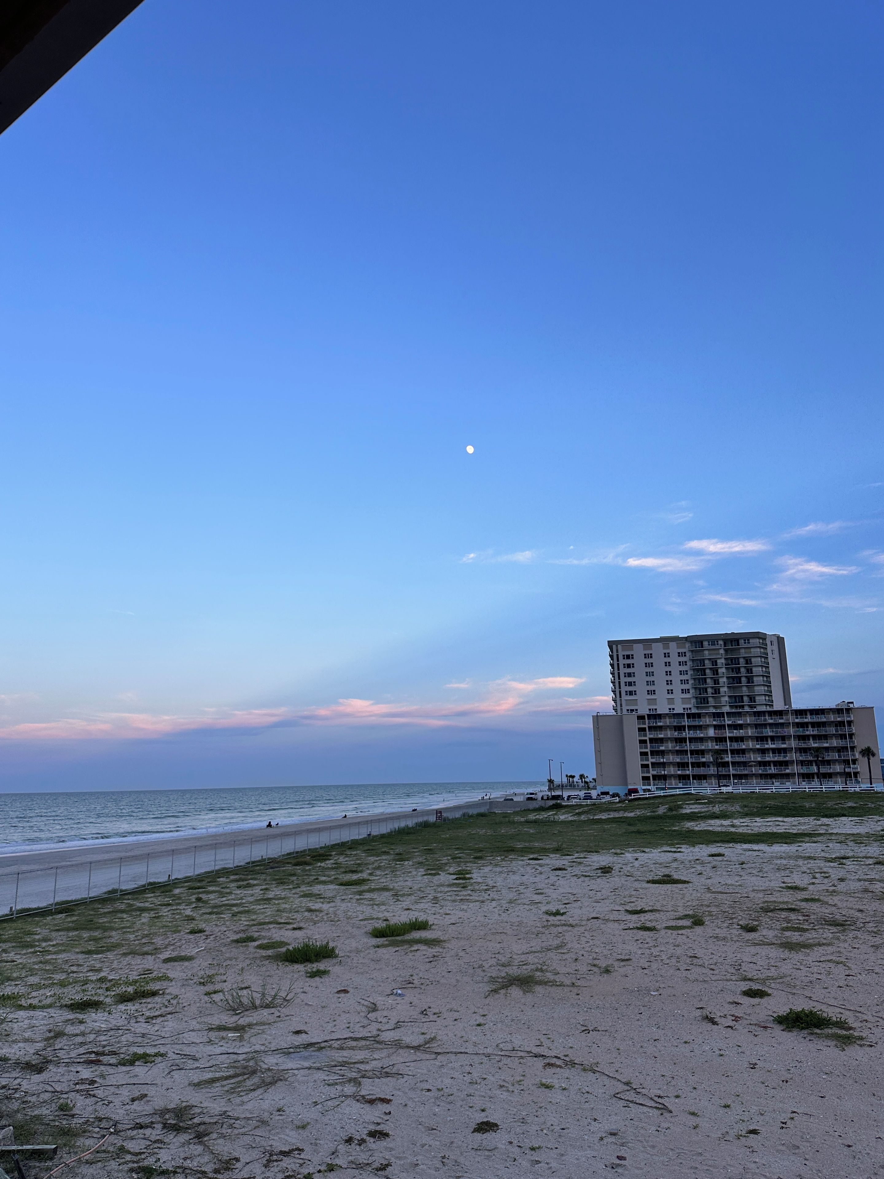 Uma praia com um edifício ao fundo.