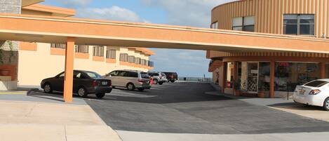 A parking lot with several cars, a building with a curved facade, and a sign indicating the establishment is open.