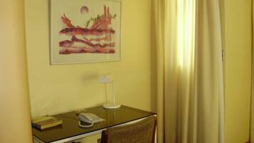 Ein Hotelzimmer mit Schreibtisch, Stuhl, Lampe und einem Bild an der Wand.