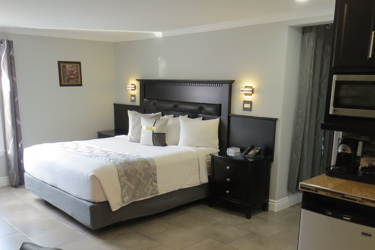 A hotel room with a large bed, bedside tables, a desk, and a microwave.