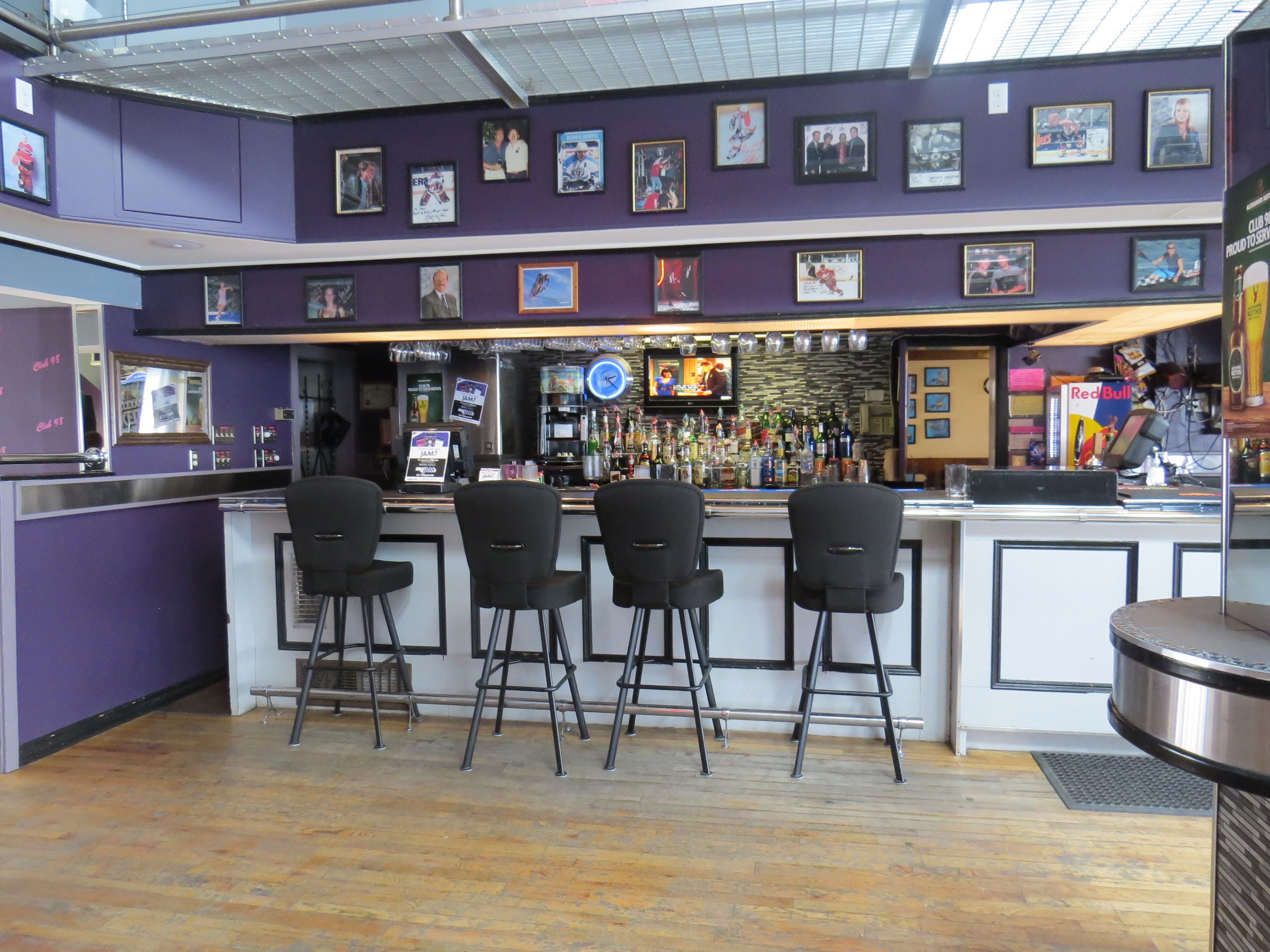 Zona de bar con barra, taburetes y una pantalla de televisión.