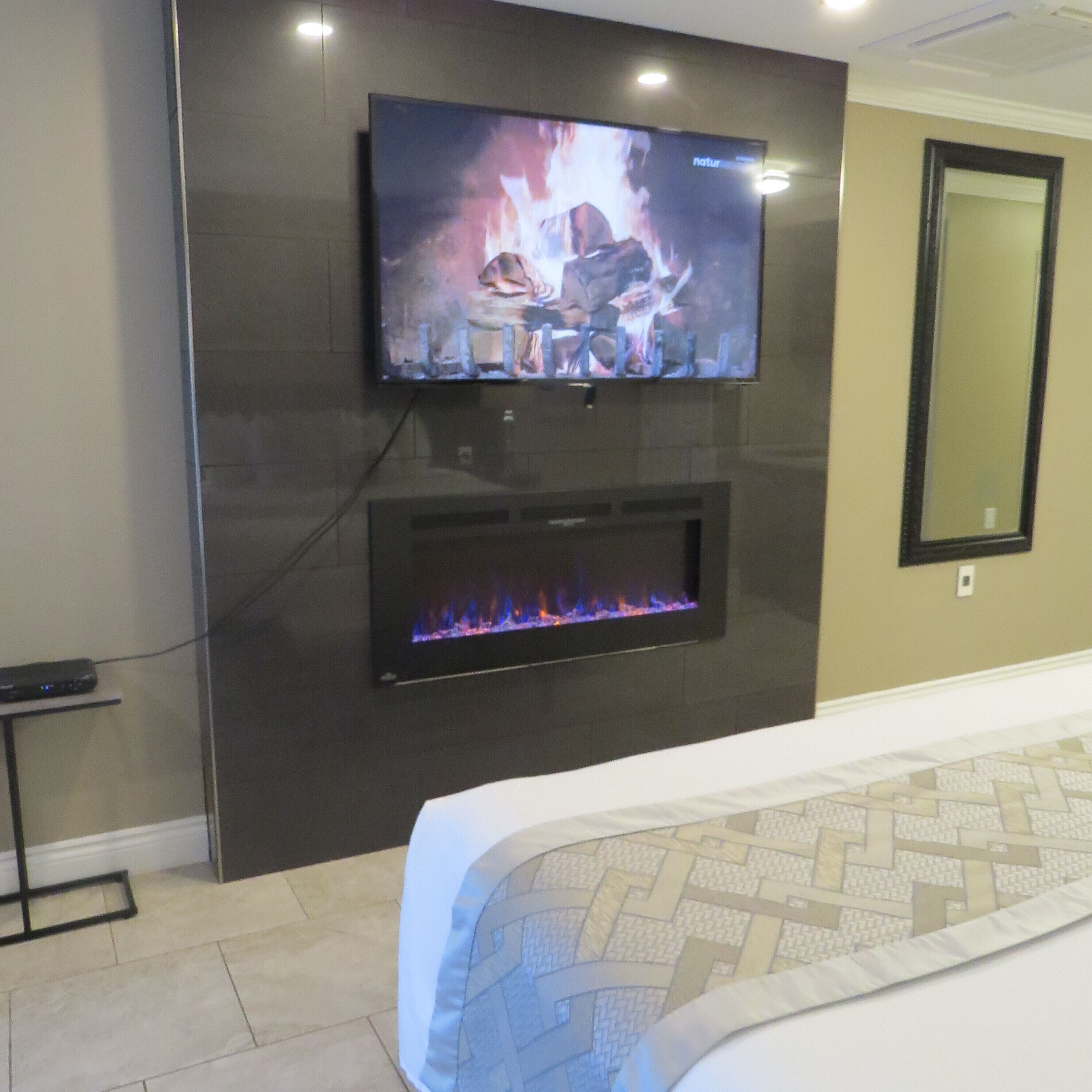 A modern hotel room with a flat-screen TV mounted above a fireplace.