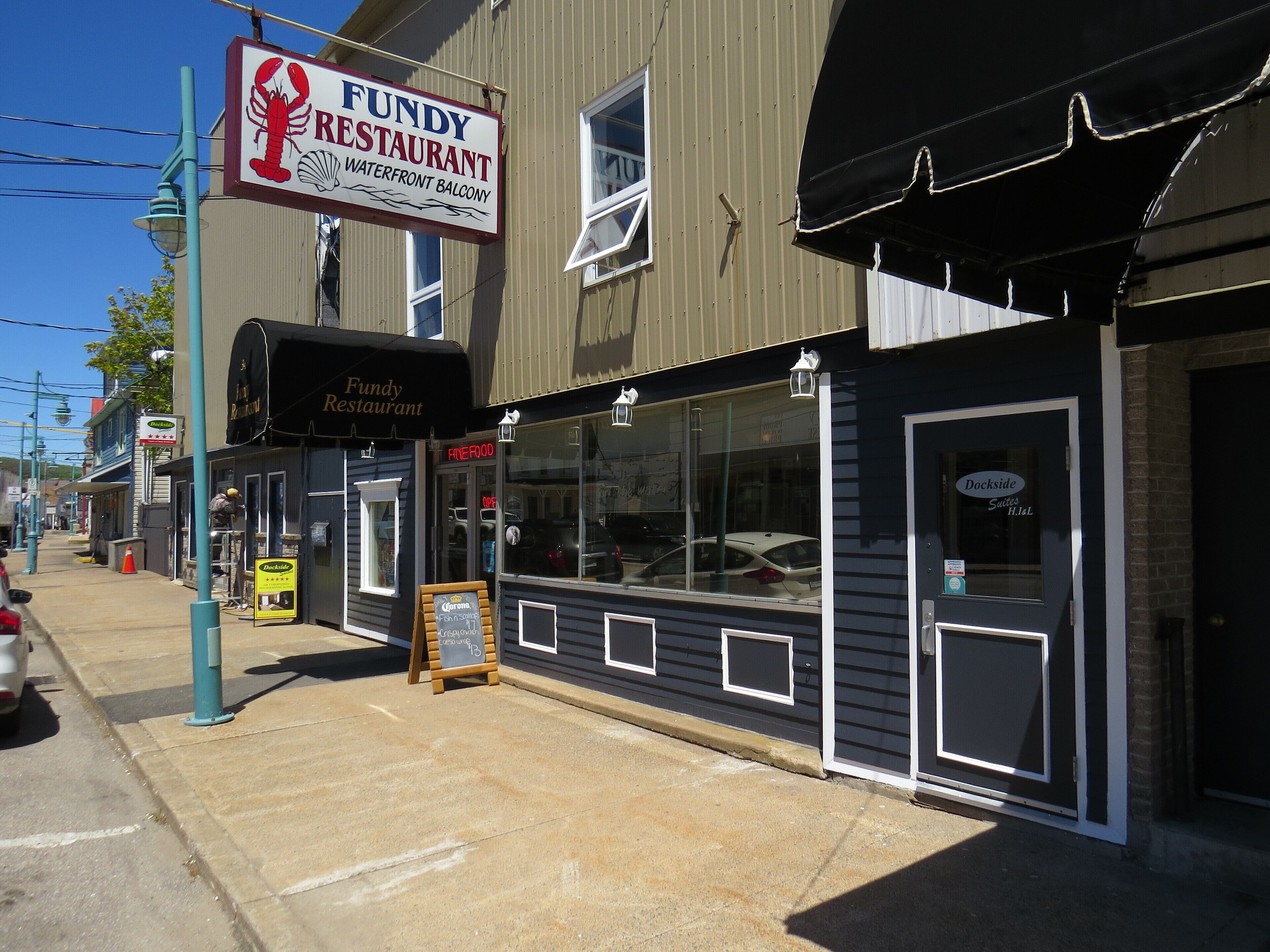 A waterfront building with a sign for 'Fundy Restaurant' and 'Dockside Suites'.