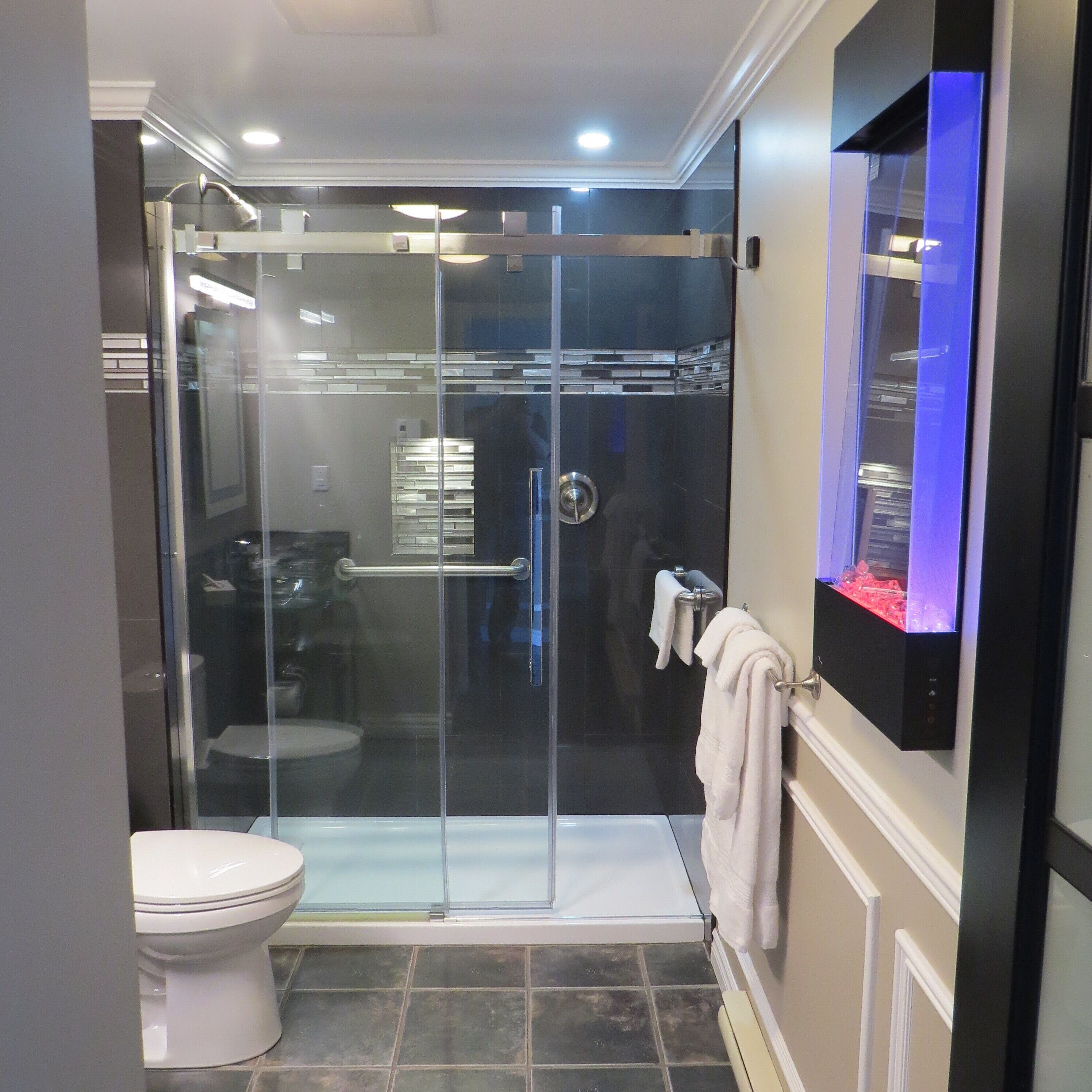 A modern bathroom with a glass-enclosed shower, a toilet, and a built-in vanity with a mirror.