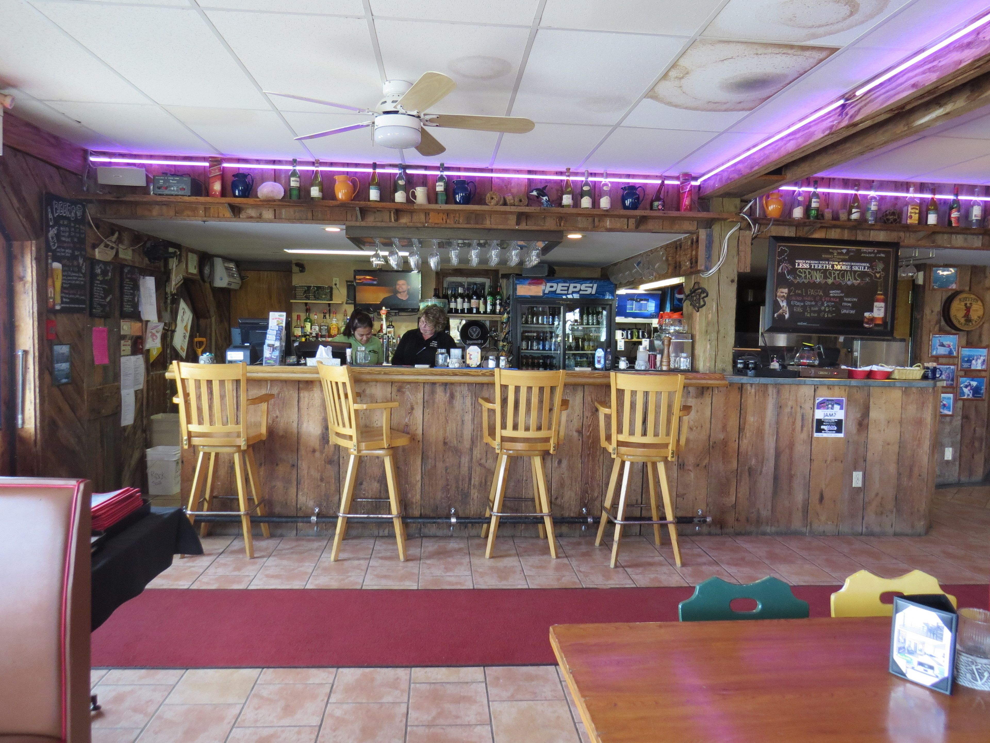A bar area with wooden chairs, a counter, and a ceiling fan.
