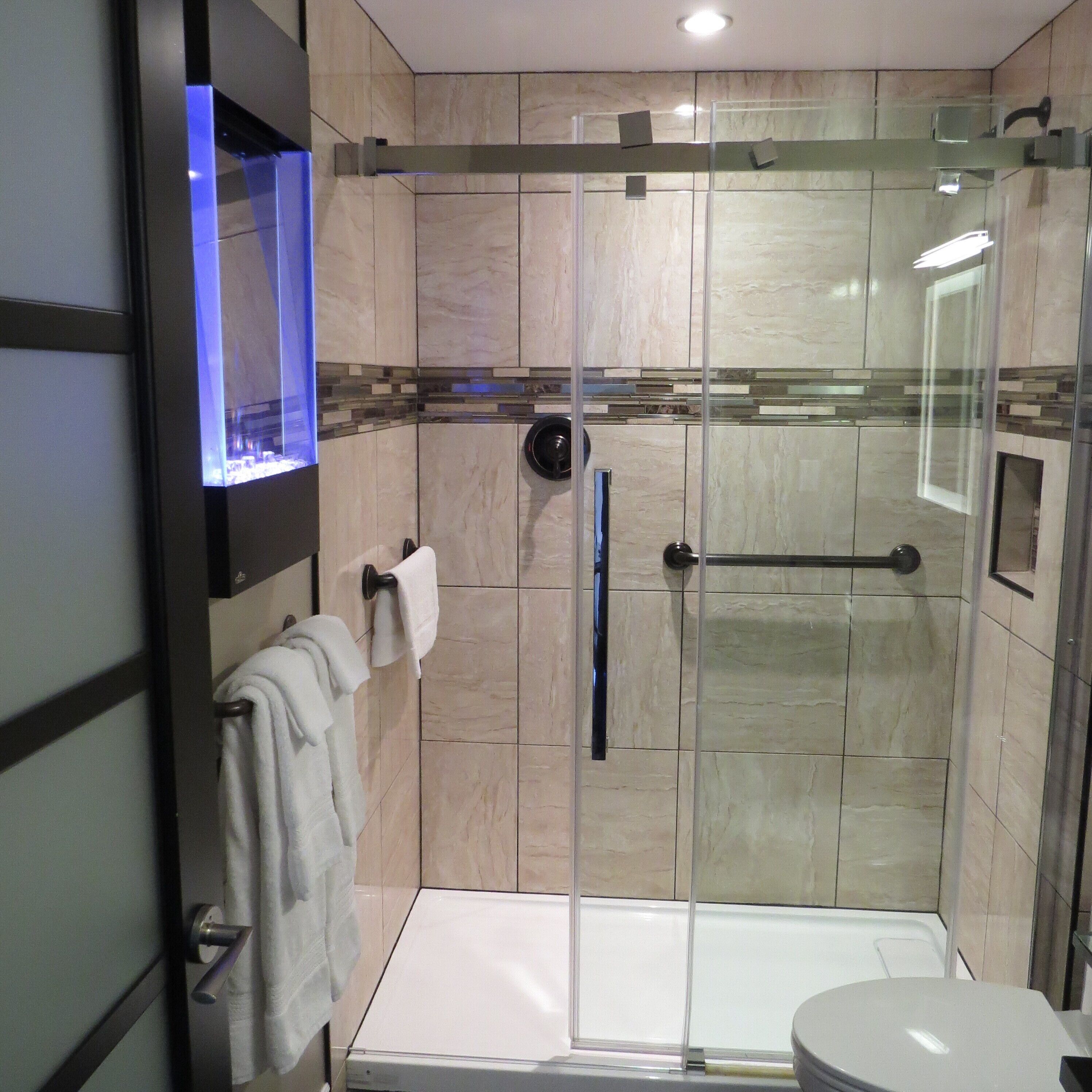 A modern bathroom with a glass-enclosed shower, a white bathtub, and a toilet.
