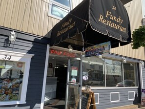 A restaurant with a sign reading "Fundy Restaurant" and a neon sign for "Fine Food."