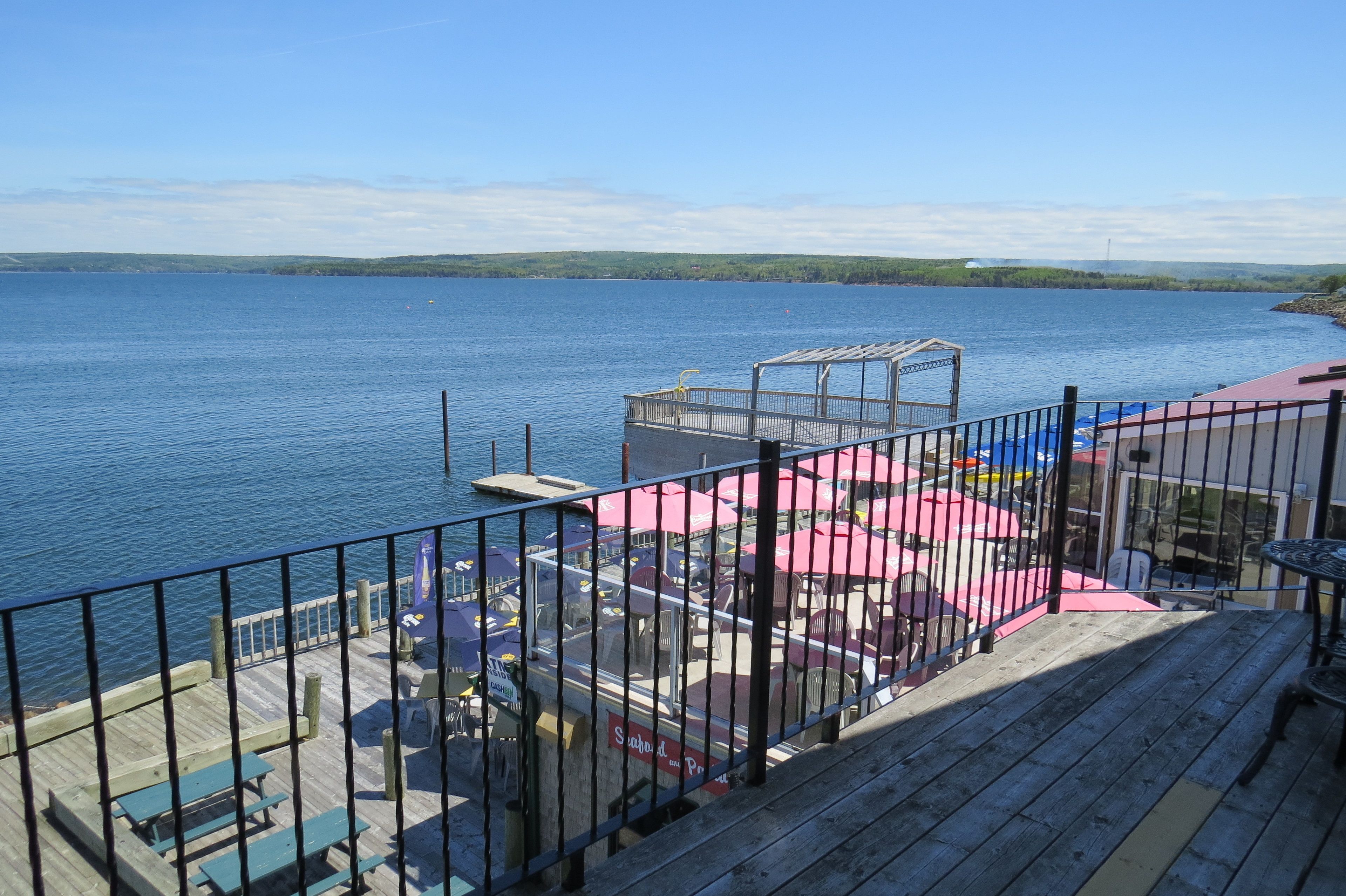 Ein Steg mit Holzdeck, Picknicktischen und Sonnenschirmen.