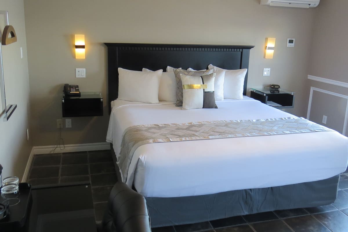 A hotel room with a large bed, two bedside tables, a chair, a desk, and a ceiling fan.