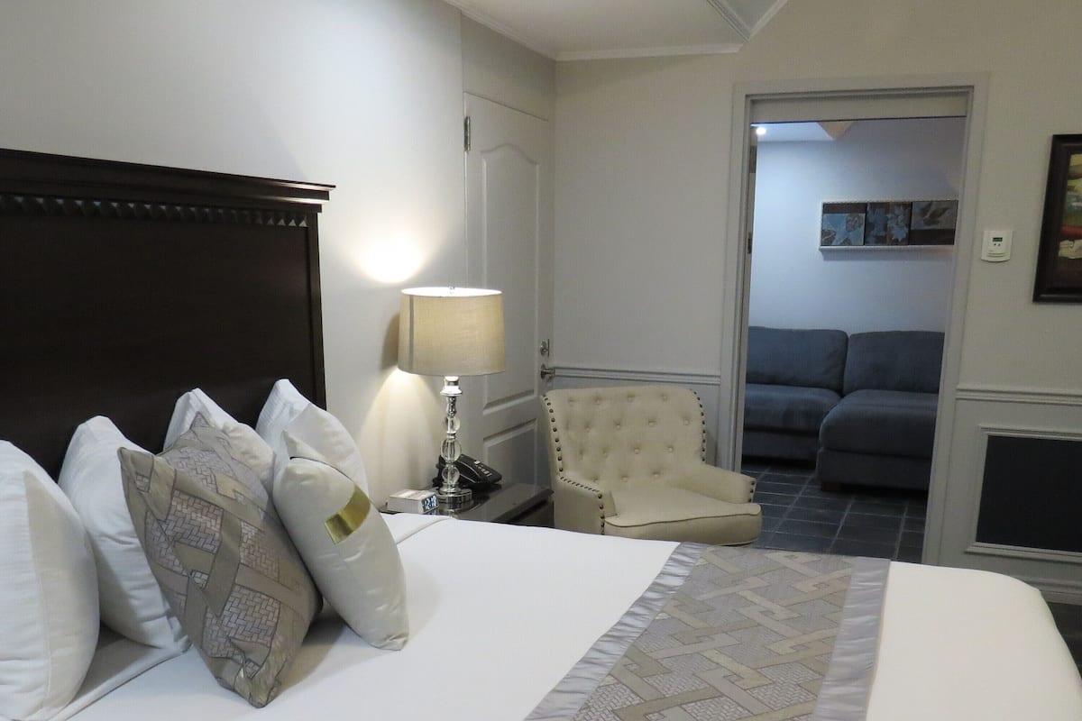 A hotel room with a large bed, a chair, a lamp, and a sofa.