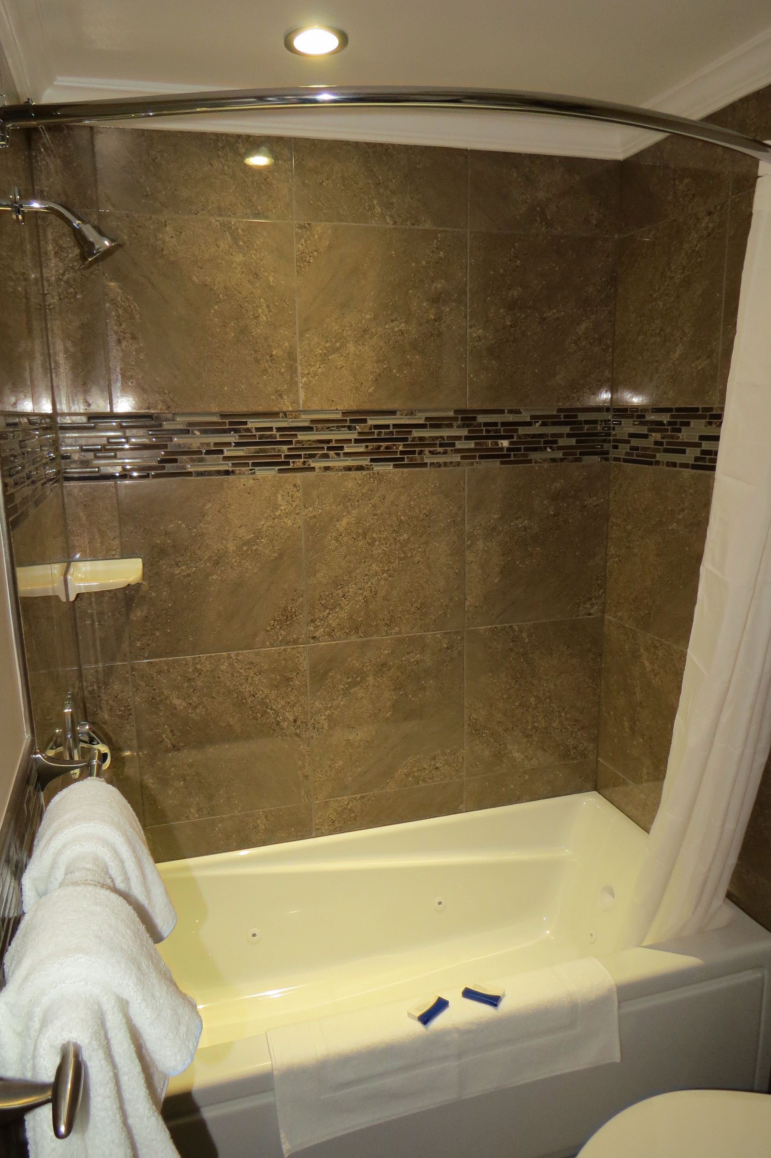 A bathroom with a bathtub, shower, and tiled walls.