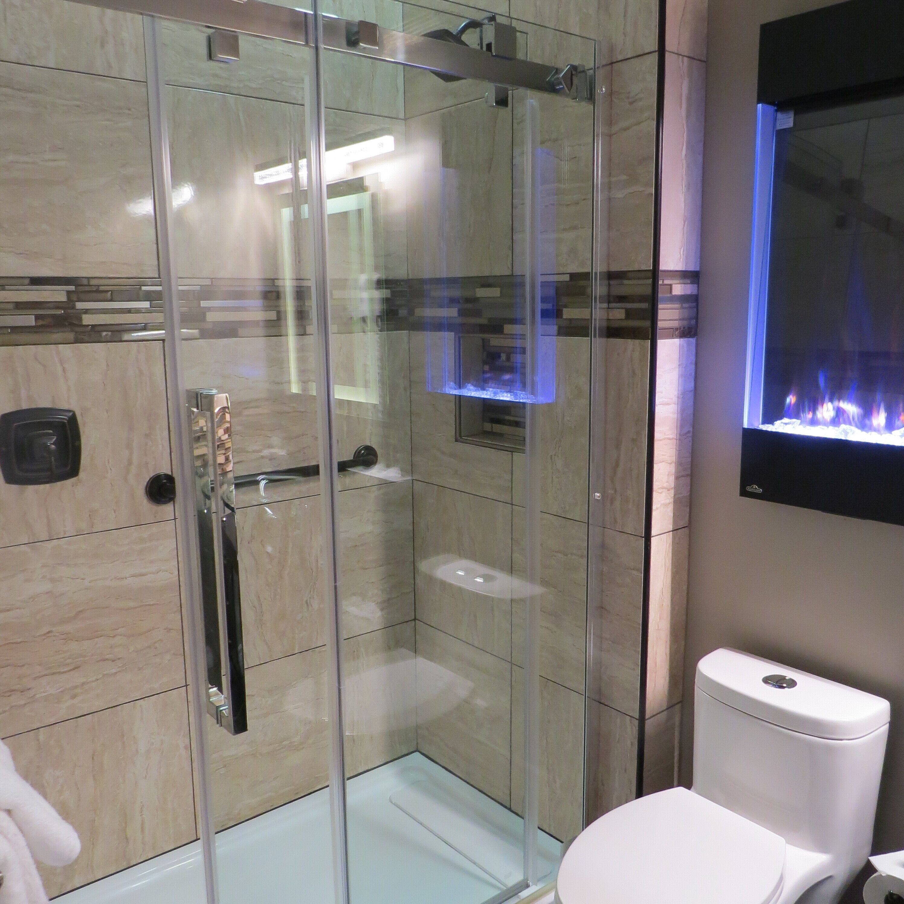 Ein modernes Badezimmer mit einer Duschkabine, einer weißen Toilette und einem am Wand befestigten Fernseher.