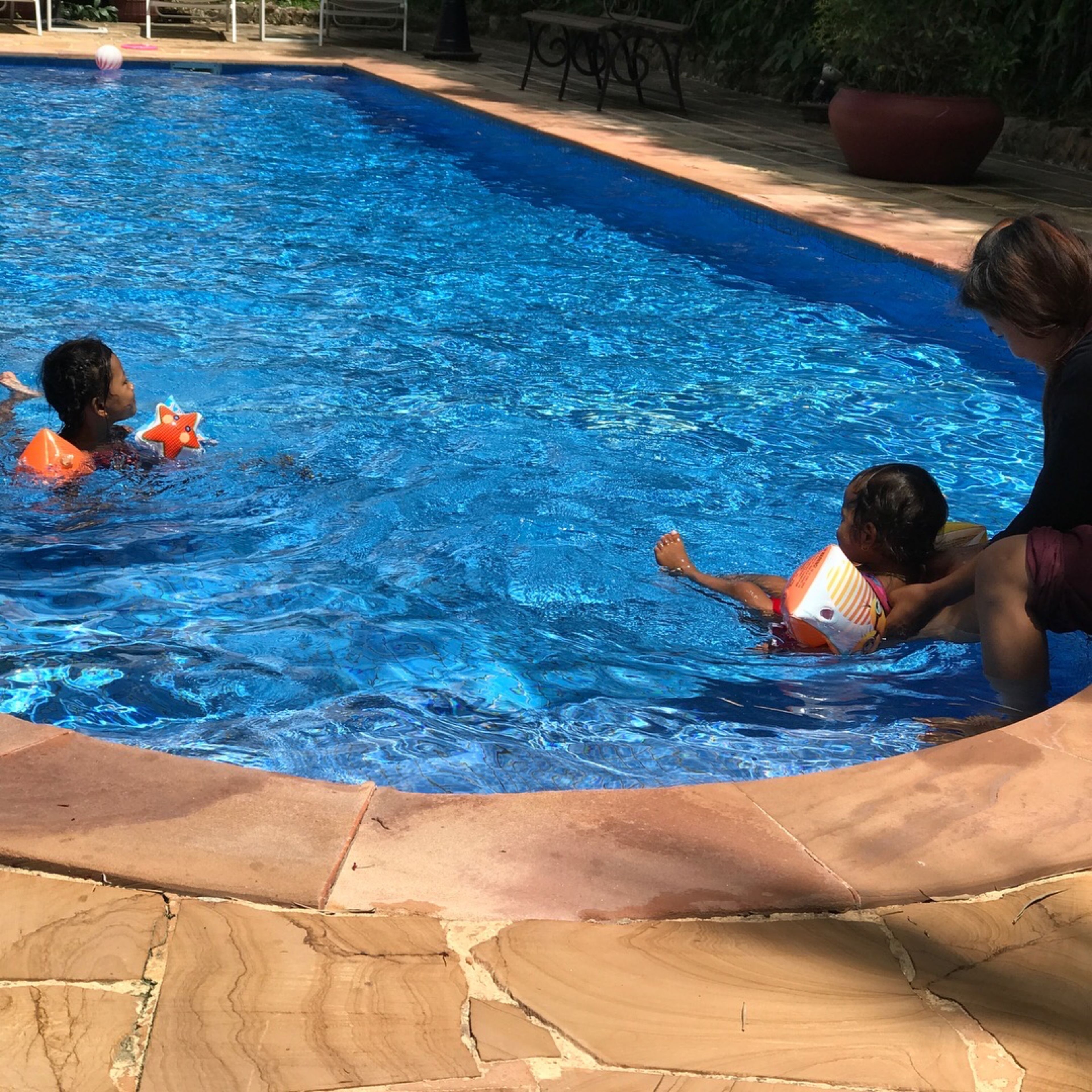 Una piscina con tres niños y un adulto.