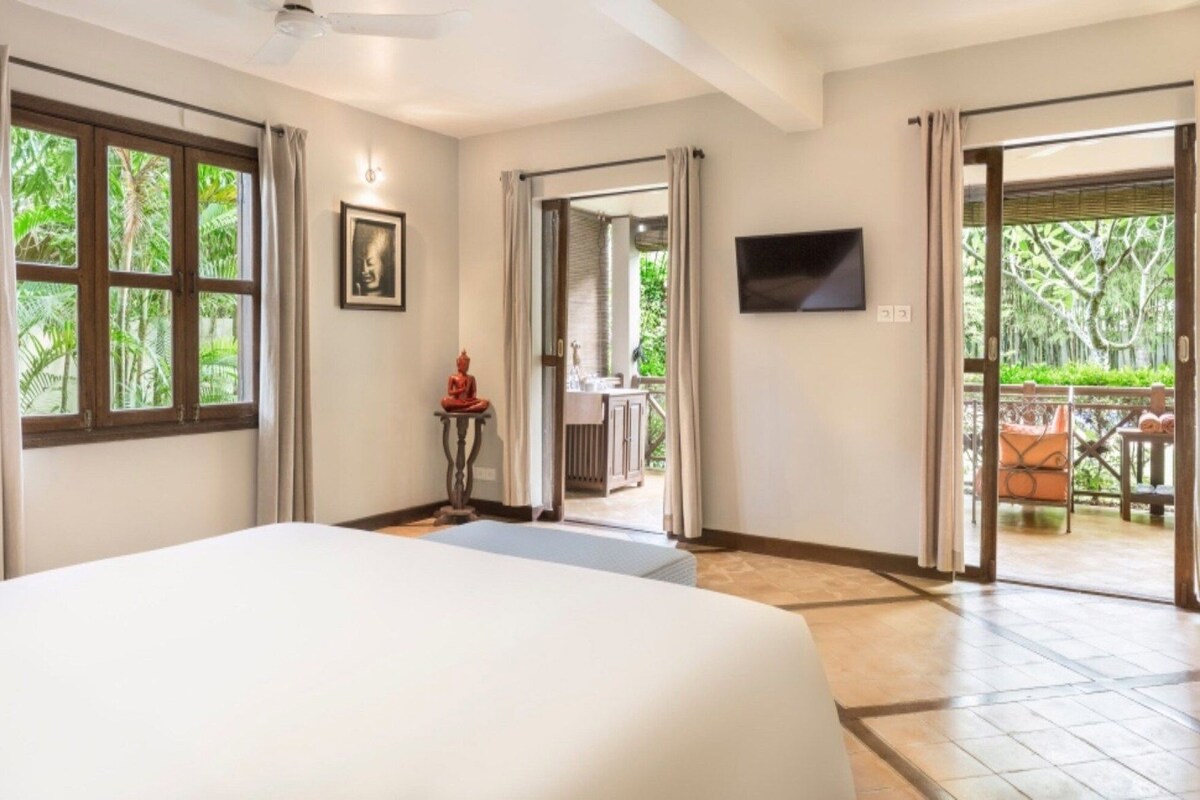 Una habitación de hotel con una cama, televisión, una estatua y vistas al exterior.